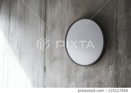 Modern Round Mirror Mounted on a Textured Concrete Wall with Natural Light Reflection 128327808