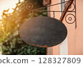 Vintage Oval Blackboard Sign Hanging Outside A Building With Warm Sunlight In The Background 128327809