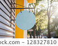 A Light Blue Blank Circular Sign Hanging Outside A Building Entrance In Sunny Weather 128327810