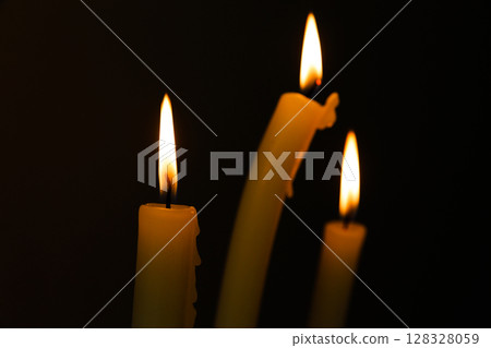 Three Illuminating Candles Dancing in the Dark, Creating a Warm and Inviting Atmosphere Perfect for Intimate Gatherings and Relaxing Moments of Tranquility and Reflection 128328059