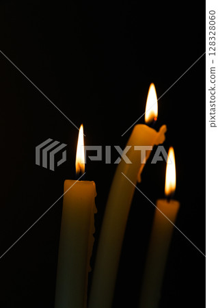 An Intimate Glimpse into the Flickering Flames of Three Candles in a Dark Setting, Illuminating the Surroundings with Warmth and Tranquility An Intimate Glimpse into the Flickering Flames of Three Candles in a Dark Setting, Illuminating the Surroundings with Warmth and Tranquility 128328060