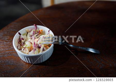 Delicious Coleslaw in a White Dish Accompanied by a Fork on a Wooden Table, Perfect for a Healthy Meal or Side Dish with Vibrant Colors and Fresh Ingredients Delicious Coleslaw in a White Dish Accompanied by a Fork on a Wooden Table, Perfect for a Healthy Meal or Side Dish with Vibrant Colors and Fresh Ingredients 128328603