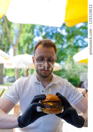A Food Enthusiast Ready to Indulge in a Delicious Burger Surrounded by Lush Greenery and Bright Umbrella Shades A Food Enthusiast Ready to Indulge in a Delicious Burger Surrounded by Lush Greenery and Bright Umbrella Shades 128328612
