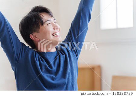 A man gets up from bed in the morning and stretches 128328759