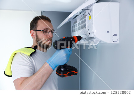 Expert Technician Performing Maintenance on Air Conditioner Unit with Precision Tools and Careful Attention to Detail in a Modern Indoor Setting 128328902