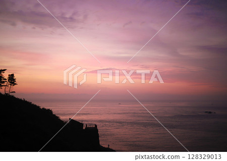 Captivating Sunset over the Tranquil Ocean with Silhouetted Trees Framing a Serene View of the Vibrant Skies and Calming Waters at Dusk Captivating Sunset over the Tranquil Ocean with Silhouetted Trees Framing a Serene View of the Vibrant Skies and Calming Waters at Dusk 128329013