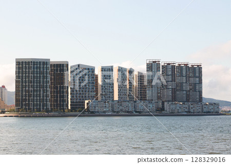 Captivating Urban Landscape Featuring Modern High-Rise Buildings Against a Clear Sky Reflected on Water's Surface, Showcasing Contemporary Architecture and City Life 128329016