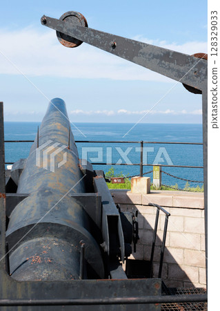 Historical Coastal Cannon Overlooking the Sea: An Imposing Artifact of Military Architecture on Display at a Coastal Fortification Historical Coastal Cannon Overlooking the Sea: An Imposing Artifact of Military Architecture on Display at a Coastal Fortification 128329033