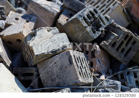 A Close-Up View of Piled and Weathered Building Bricks Displaying Distinctive Shapes and Textures in Direct Sunlight on a Construction Site A Close-Up View of Piled and Weathered Building Bricks Displaying Distinctive Shapes and Textures in Direct Sunlight on a Construction Site 128329380