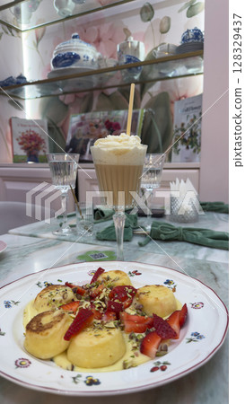 Delightful Dessert Presentation Featuring Sweet Dumplings and Fresh Strawberries with Creamy Beverage, Perfect for Indulging in a Luxurious Afternoon Treat at the Caf 128329437