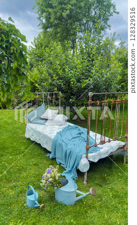 A Cozy Outdoor Retreat Featuring a Charming Vintage Bed Surrounded by Lush Greenery and Beautiful Flowers in a Peaceful Garden Setting in the Heart of Nature 128329516