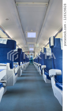A Spacious Train Interior Featuring Rows of Plush Blue Seats with a Clear Perspective Down the Aisle and Modern Lighting Fixtures for a Comfortable Journey Experience 128329828