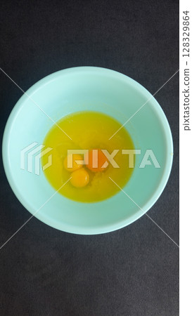 Delicious and Freshly Cracked Eggs in a Light Blue Bowl Ready for Cooking or Baking Against a Dark Background for a Stunning Visual Presentation Delicious and Freshly Cracked Eggs in a Light Blue Bowl Ready for Cooking or Baking Against a Dark Background for a Stunning Visual Presentation 128329864