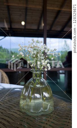 A Delicate Display of Nature: A Vase with White Flowers Capturing Serenity and Simplicity in a Cozy Interior Space Surrounded by Natural Beauty 128329871