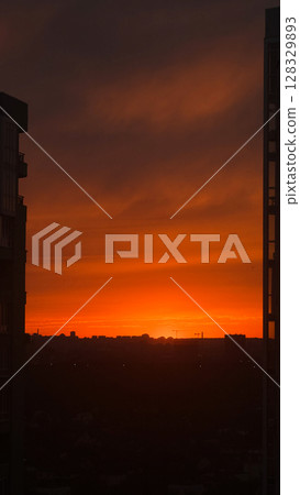 Stunning Urban Sunset Showcasing an Orange Glow with Silhouetted Buildings Against the Vibrant Evening Sky, Capturing the Essence of a Peaceful Twilight Moment 128329893