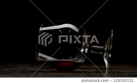 A Glass of Red Wine Spilled on a Wooden Surface, Creating a Unique Visual Contrast Against a Black Background 128330132