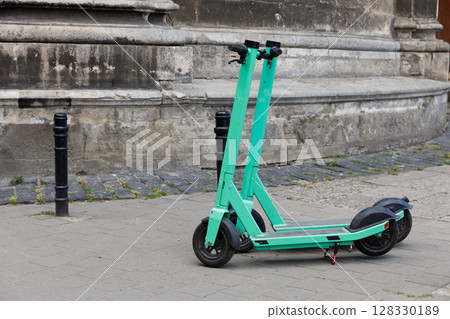 A Vibrant Green Electric Scooter Parked on a City Street, Showcasing Modern Urban Mobility Solutions Amidst Historic Architectural Backdrop A Vibrant Green Electric Scooter Parked on a City Street, Showcasing Modern Urban Mobility Solutions Amidst Historic Architectural Backdrop 128330189