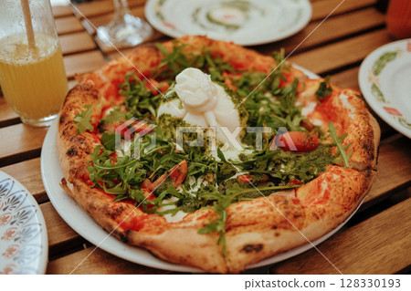 Freshly baked pizza topped with creamy burrata, tomatoes and fresh rucola leaves Freshly baked pizza topped with creamy burrata, tomatoes and fresh rucola leaves 128330193