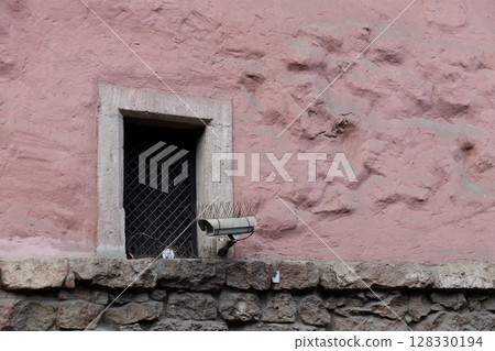 An Intriguing View of a Window Surrounded by a Textured Pink Wall Featuring a Security Camera for Surveillance and an Artistic Blend of Materials An Intriguing View of a Window Surrounded by a Textured Pink Wall Featuring a Security Camera for Surveillance and an Artistic Blend of Materials 128330194