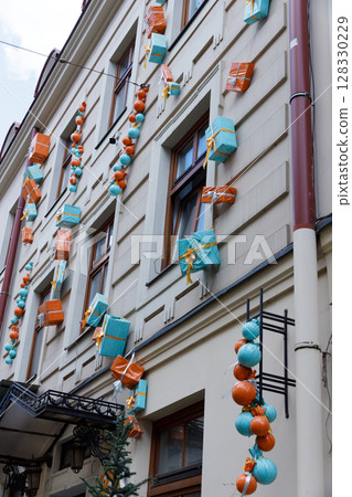 Colorful Holiday Decorations Adorning a Building Exterior with Packages and Lanterns in Vibrant Shades of Orange and Teal Creating a Festive Atmosphere for Everyone 128330229