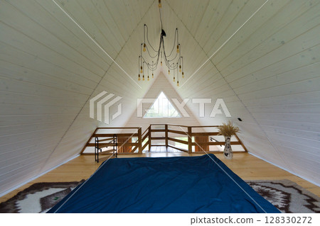 Serene A-Frame Loft Bedroom with Modern Decor and Cozy Atmosphere Enhanced by Natural Light Filtering Through Triangular Window View 128330272