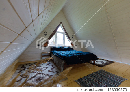 Cozy and Stylish Bedroom Featuring A Unique A-Frame Design with Natural Wood Accents and Contemporary Furnishings for a Relaxing Retreat Experience 128330273