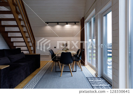 Stylishly Designed Modern Living Room Featuring Wooden Elements and a Dining Area with Cozy Ambiance, Ideal for Family Gatherings and Relaxation in a Contemporary Cabin Stylishly Designed Modern Living Room Featuring Wooden Elements and a Dining Area with Cozy Ambiance, Ideal for Family Gatherings and Relaxation in a Contemporary Cabin 128330641