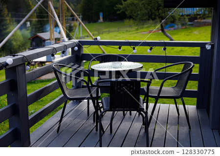 Charming Outdoor Deck Space with Elegant Table and Chairs Perfect for Relaxation and Enjoying Scenic Views Surrounded by Nature's Beauty and Warm Evening Lights 128330775