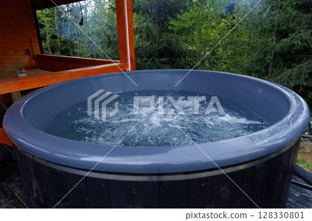 Relaxing Outdoor Hot Tub Surrounded by Lush Greenery in a Peaceful Setting, Perfect for Unwinding and Enjoying Nature's Beauty and Serene Ambiance 128330801