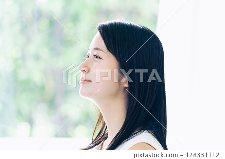 Portrait of a young woman standing by the window 128331112