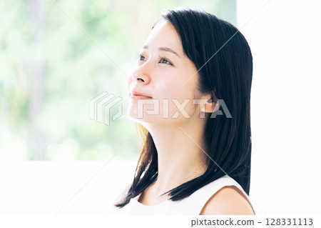 Portrait of a young woman standing by the window 128331113