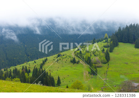 Serene Mountain Landscape with Lush Green Hills and Misty Clouds Above in a Peaceful Natural Setting in Early Spring Serene Mountain Landscape with Lush Green Hills and Misty Clouds Above in a Peaceful Natural Setting in Early Spring 128331386