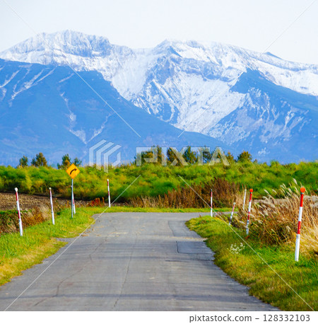 北海道的秋季風景,白雪皚皚的山脈和向右彎曲的道路 北海道的秋季風景,白雪皚皚的山脈和向右彎曲的道路 128332103