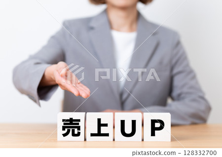 A middle-aged female business woman wearing a suit and a sales increase block A middle-aged female business woman wearing a suit and a sales increase block 128332700
