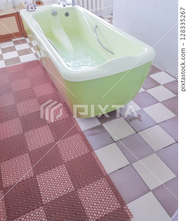 Modern spa room interior with an olive-colored bathtub for water therapy treatments, vertical 128335267