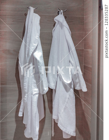 Two white robes on a rack in the hotel bathroom Two white robes on a rack in the hotel bathroom 128335287