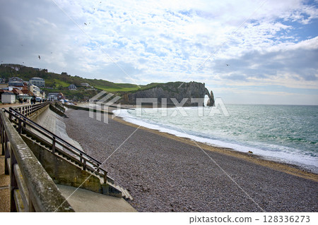 Etretat promenade and beach with sea arch under dramatic sky 128336273