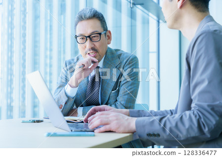 Two middle-aged businessmen having a meeting. Filming cooperation: SKY Perfect Tokyo Media Center Two middle-aged businessmen having a meeting. Filming cooperation: SKY Perfect Tokyo Media Center 128336477