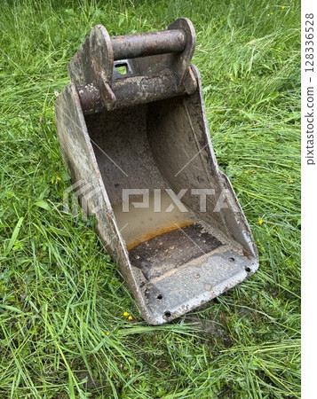 Rusty metal bucket is sitting on the grass 128336528