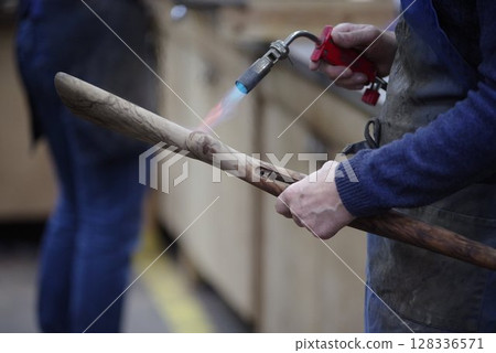 Man is holding a wooden stick with a flame on it Man is holding a wooden stick with a flame on it 128336571