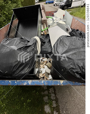 Dumpster is full of trash, including a pile of plastic bags 128336641