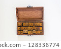 Handcrafted wooden box containing complete alphabet rubber stamps with uppercase letters and punctuation marks, arranged in three neat rows. Perfect for crafting, journaling, and traditional printing  128336774