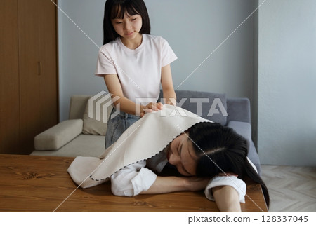 An image of a daughter covering her mother who has fallen asleep due to fatigue 128337045