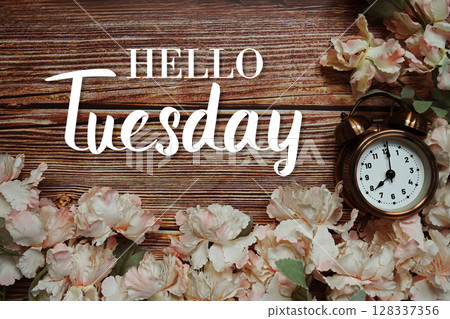 Hello Tuesday text with alarm clock and flowers decoration on wooden background Hello Tuesday text with alarm clock and flowers decoration on wooden background 128337356