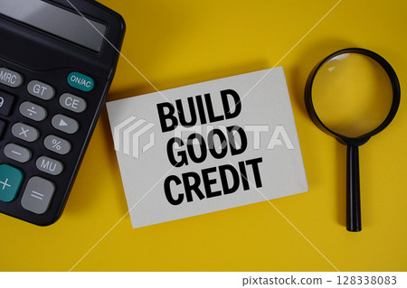 Build Good Credit text with magnifying glass anc calculator on yellow background 128338083