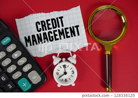 Credit Management text with alarm clock, magnifying glass anc calculator on red background 128338120