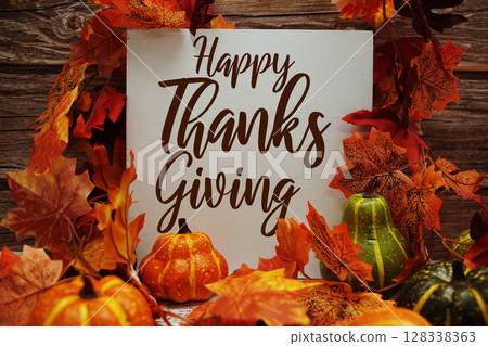 Happy Thanksgiving text message with pumpkins and maple leaf decoration on wooden background Happy Thanksgiving text message with pumpkins and maple leaf decoration on wooden background 128338363