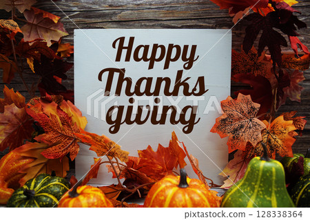 Happy Thanksgiving text message with pumpkins and maple leaf decoration on wooden background Happy Thanksgiving text message with pumpkins and maple leaf decoration on wooden background 128338364