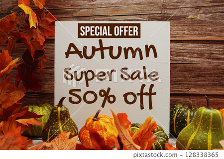 Autumn Super Sale 50% Off Special Offer text with pumkins and maple leaf decoration on wooden background 128338365