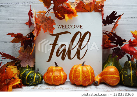 Welcome Fall text with pumkins and maple leaf decoration on wooden background 128338366